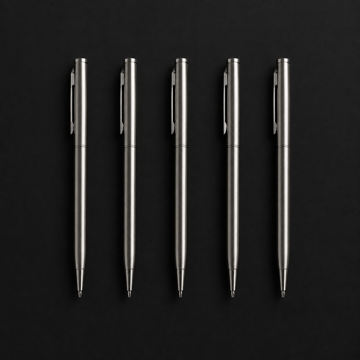 Five machined steel pens lined up on black